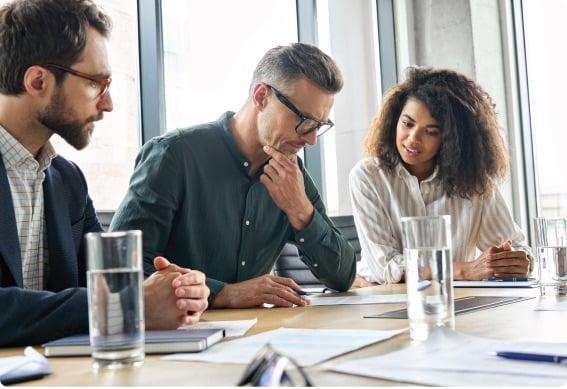 a group of people sitting at a table looking at papers