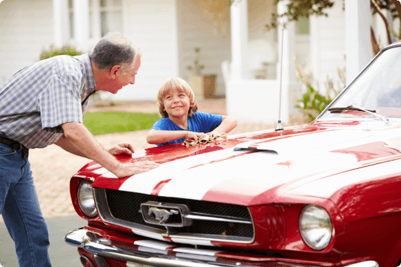 A grandparent washing their car with their grandchild.