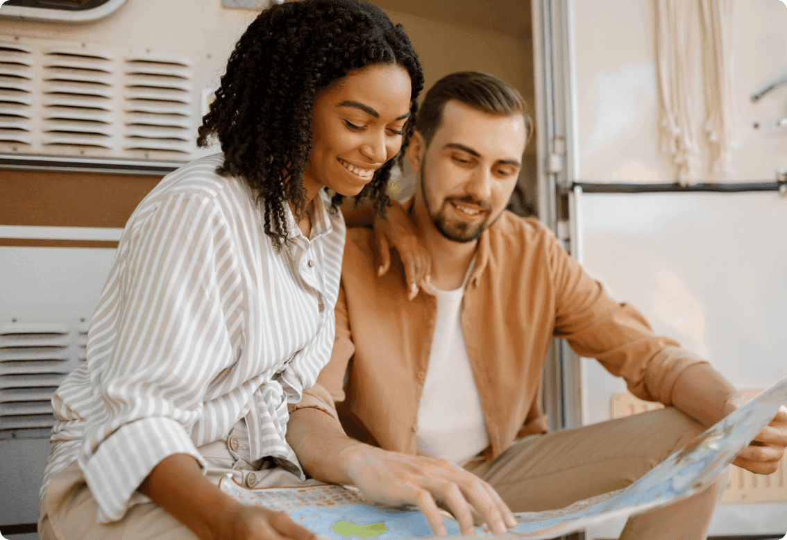 A man and a woman looking at a map in front of an RV