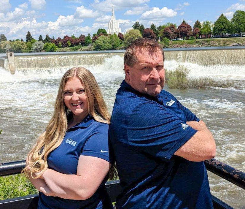 a man and woman posing for a picture next to a waterfall