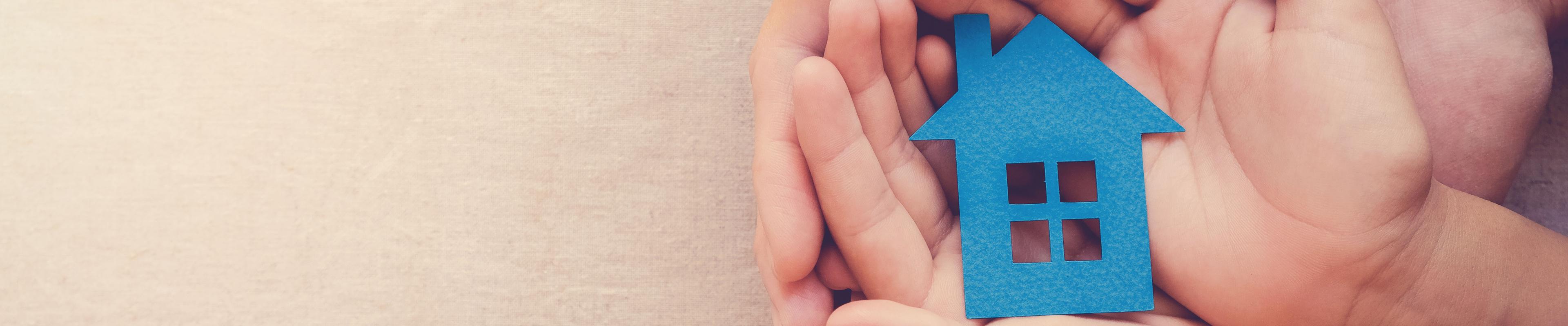 Child holding a paper cut out of a house