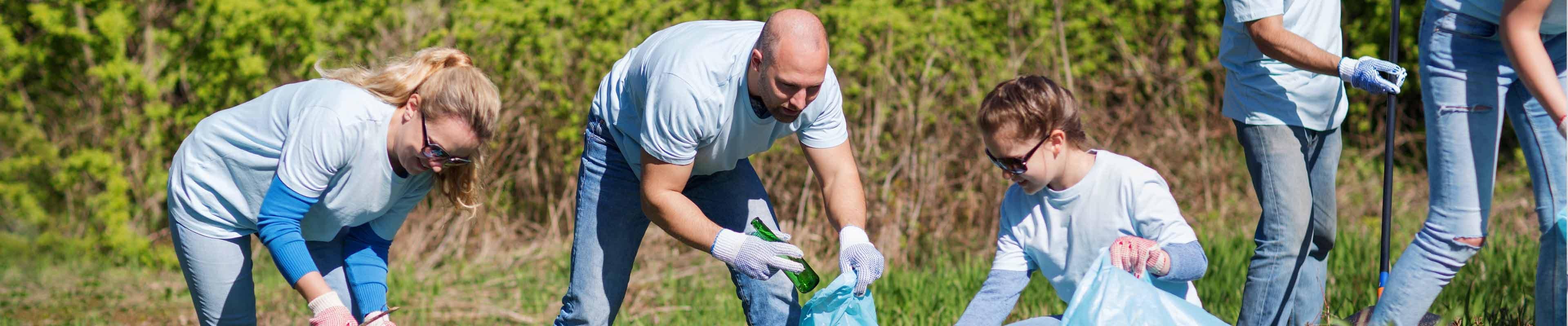 Coworkers volunteering by picking up litter along a highway.