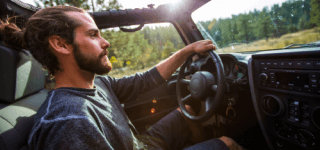 A man driving a car in a wooded area