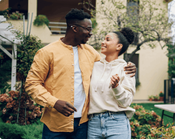 A happy couple standing in front of their home.