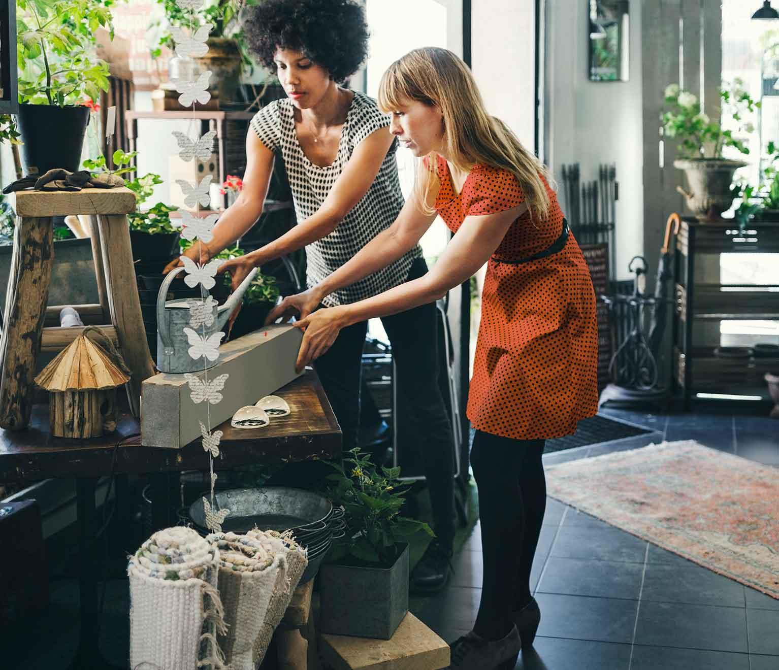 a couple of women looking at a model of a house