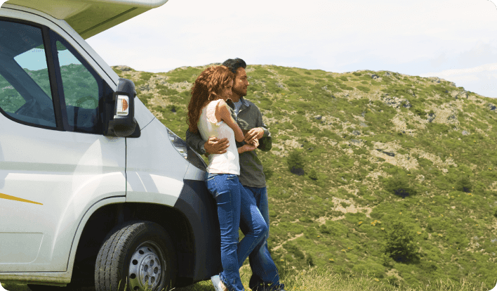 Couple holding each other intimately in front of their parked RV and enjoying the view